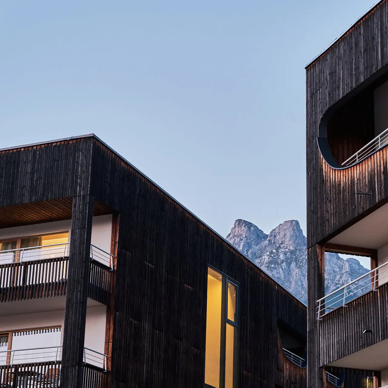 Hotel Een close-up van het hotelgebouw met balkons en de bergen op de achtergrond.