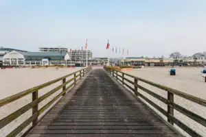 Holzbrücke über einem Strand mit klarem Himmel im Hintergrund.