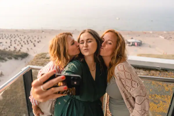 Balkon Eine Gruppe von Frauen stehen auf einem Balkon mit Meerblick und macht ein Selfie.