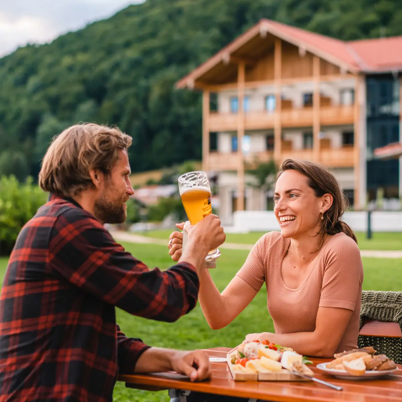 Biertuin in Ruhpolding Een man en een vrouw zitten aan een tafel met eten en drinken.