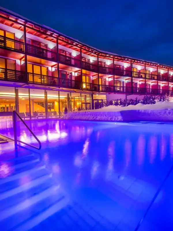 Buitenzwembad 's nachts Een gebouw met een zwembad en sneeuw op de voorgrond.