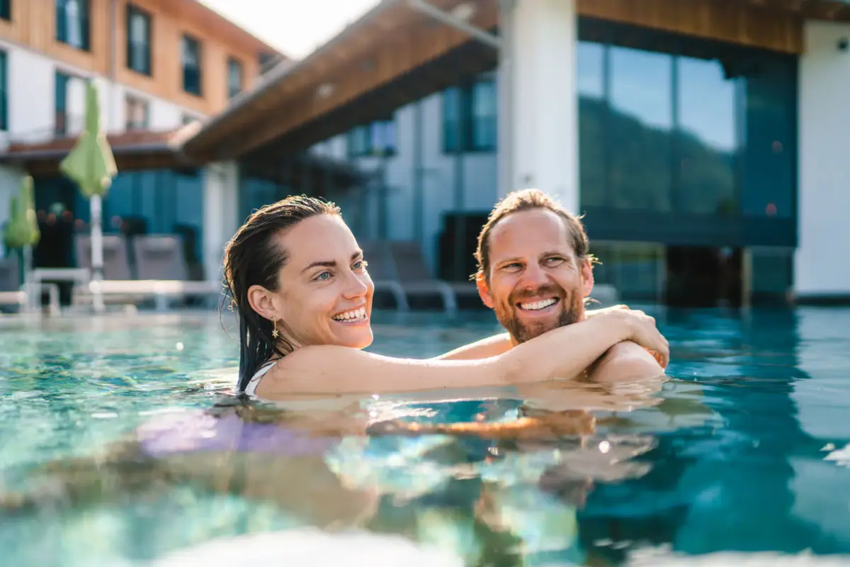 Buitenzwembad bij aja Ruhpolding Een man en een vrouw lachen in een zwembad.