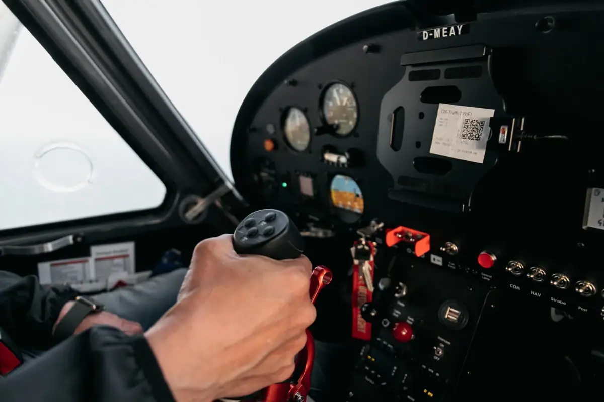Een hand houdt een hendel vast in de cockpit van een vliegtuig.