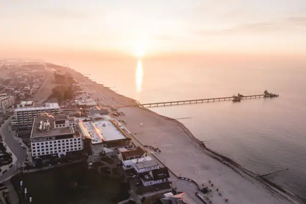 Strand mit einem Pier und Gebäuden bei Sonnenuntergang.