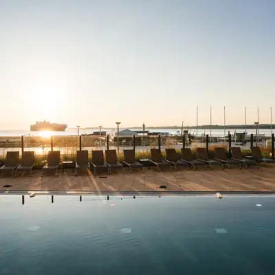 Buitenzwembad Een zwembad met stoelen en een boot op de achtergrond.