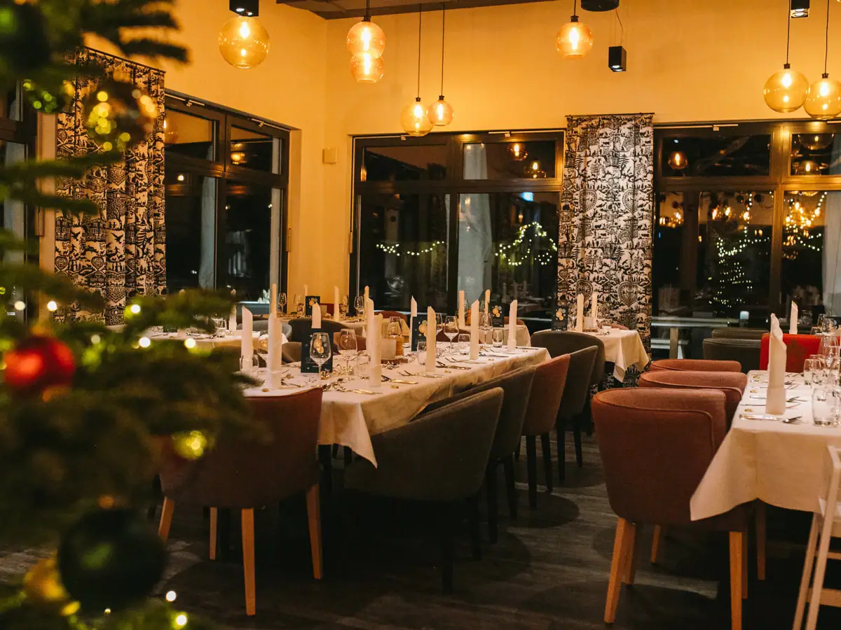 Een kamer met tafels en stoelen en een kerstboom.