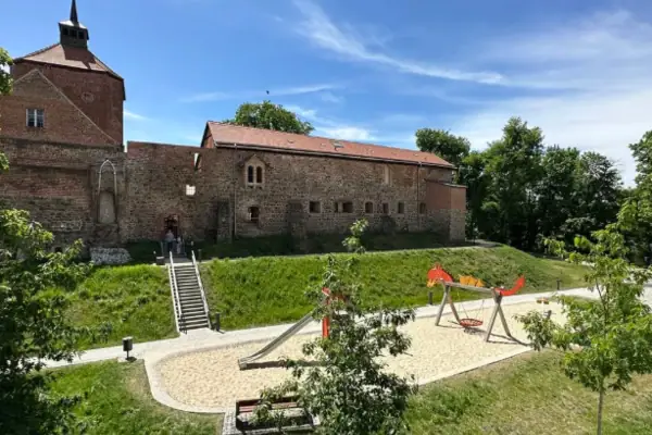 Een speeltuin voor een gebouw met bomen en een blauwe lucht.