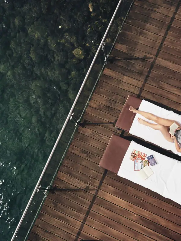 Ligstoel bij het meer Een vrouw ligt op een ligstoel naast het water.