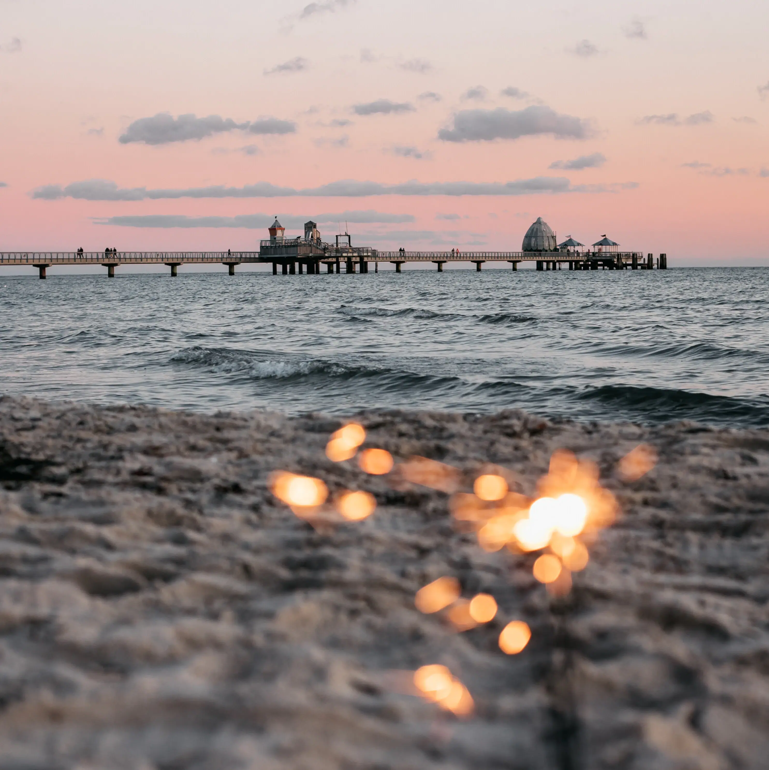 Een strand met een pier op de achtergrond.