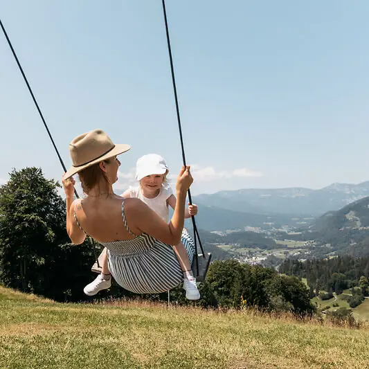 Een moeder met haar kind op een schommel tijdens een gezinsvakantie in Ruhpolding.