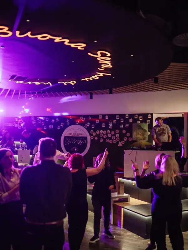 Een groep mensen in een kamer met een podium en een bord.