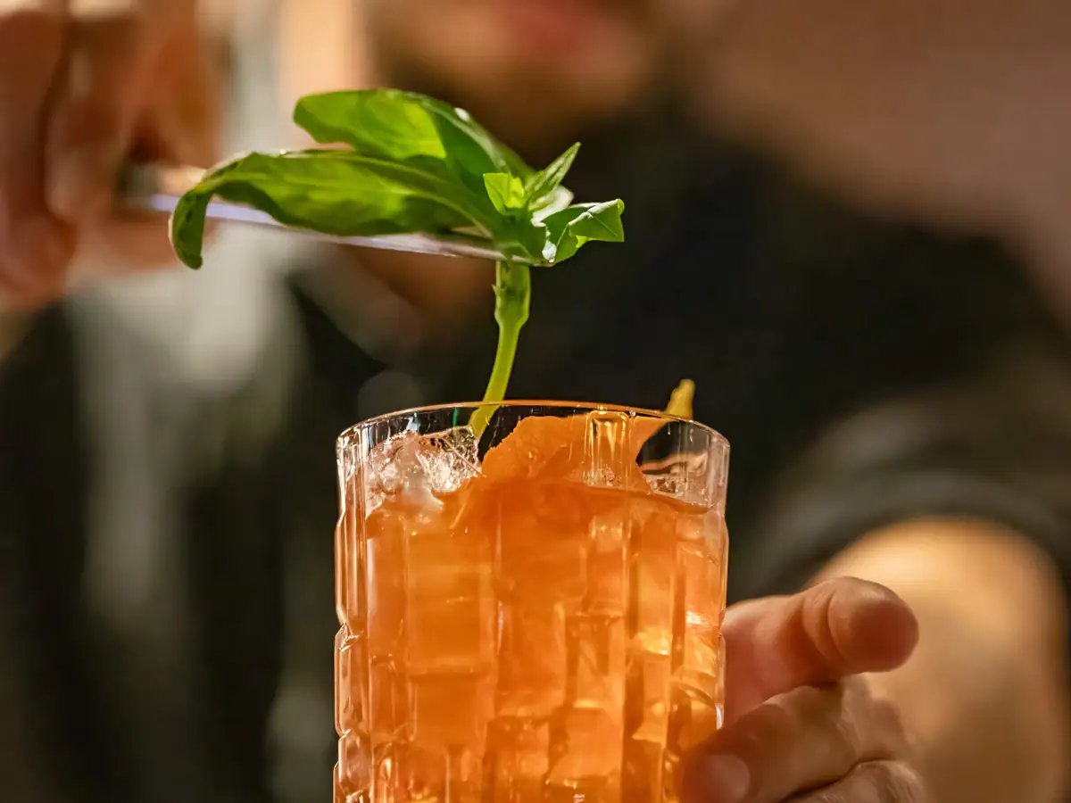 Een man houdt een mes boven een glas met drank.