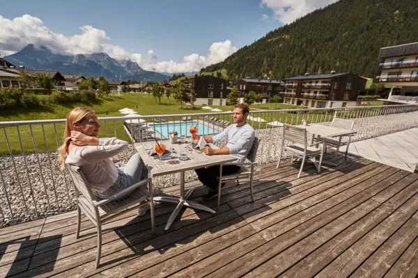 Een man en een vrouw zitten aan een tafel op een terras.