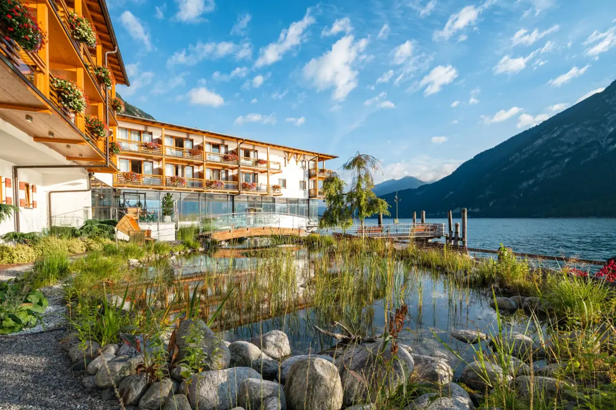Vorstelijk huis aan het Achenmeer Een gebouw met water en bergen op de achtergrond.