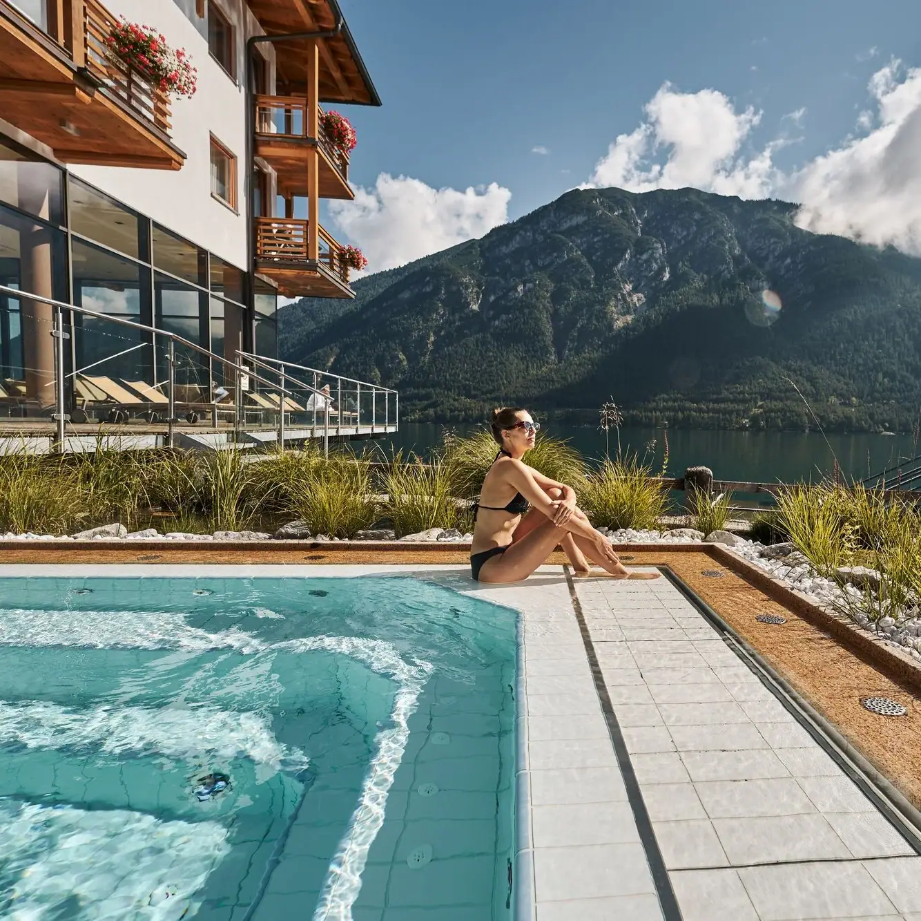 Whirlpool Een vrouw zit bij een zwembad met een berg op de achtergrond.