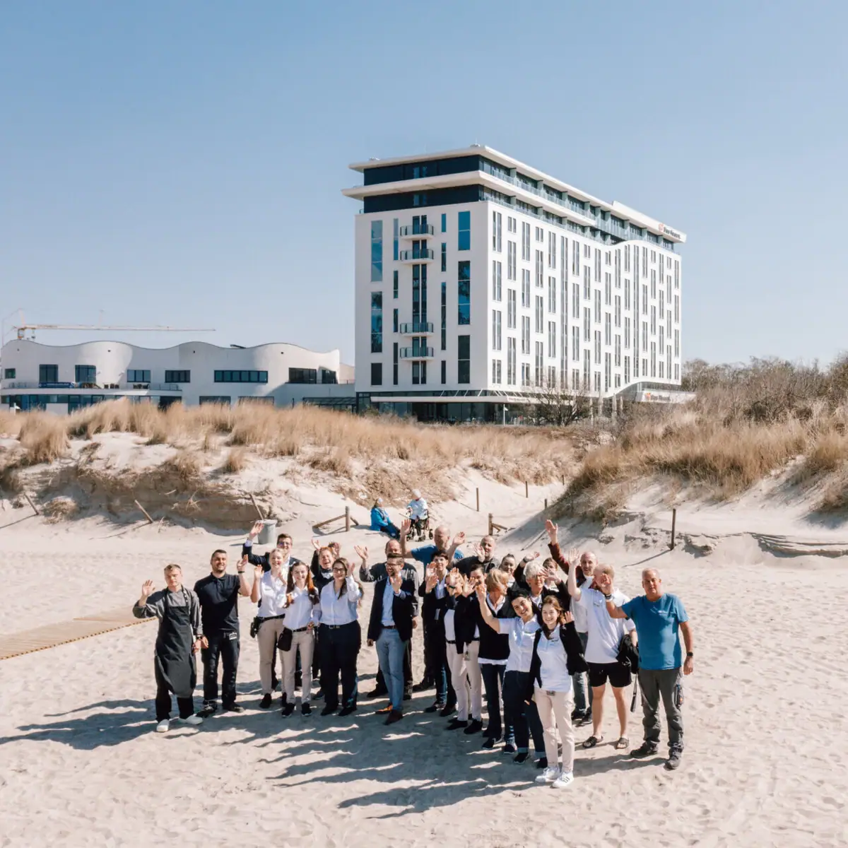 Een groep mensen poseert voor een gebouw.