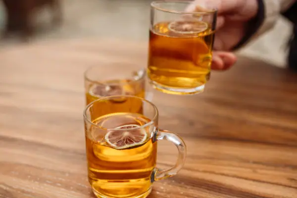 Tee Eine Hand hält ein Glas mit einem Getränk.