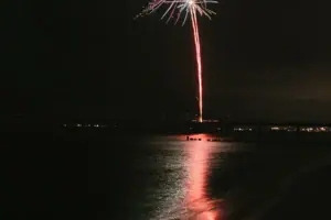 Vuurwerk aan de nachtelijke hemel boven het water