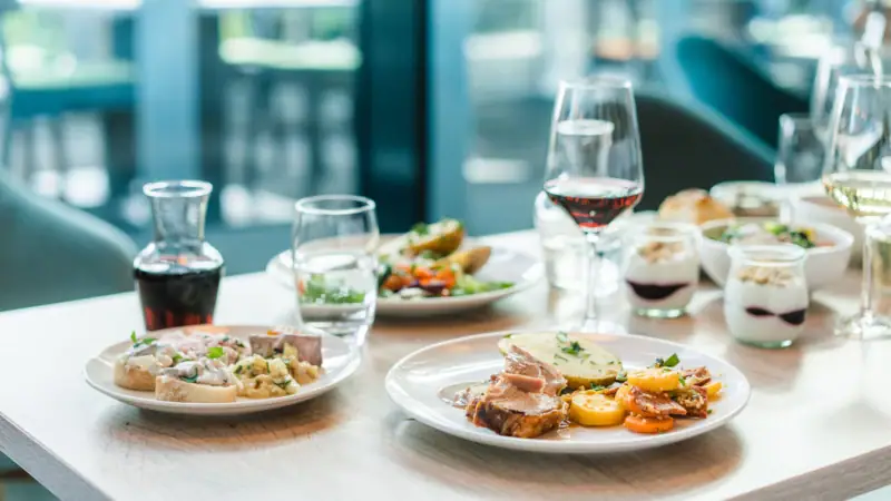 Een tafel met borden vol eten en glazen wijn.