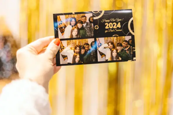 Hand houdt een kaart vast met een groep mensen. De kaart is gevuld met foto's van de avond.