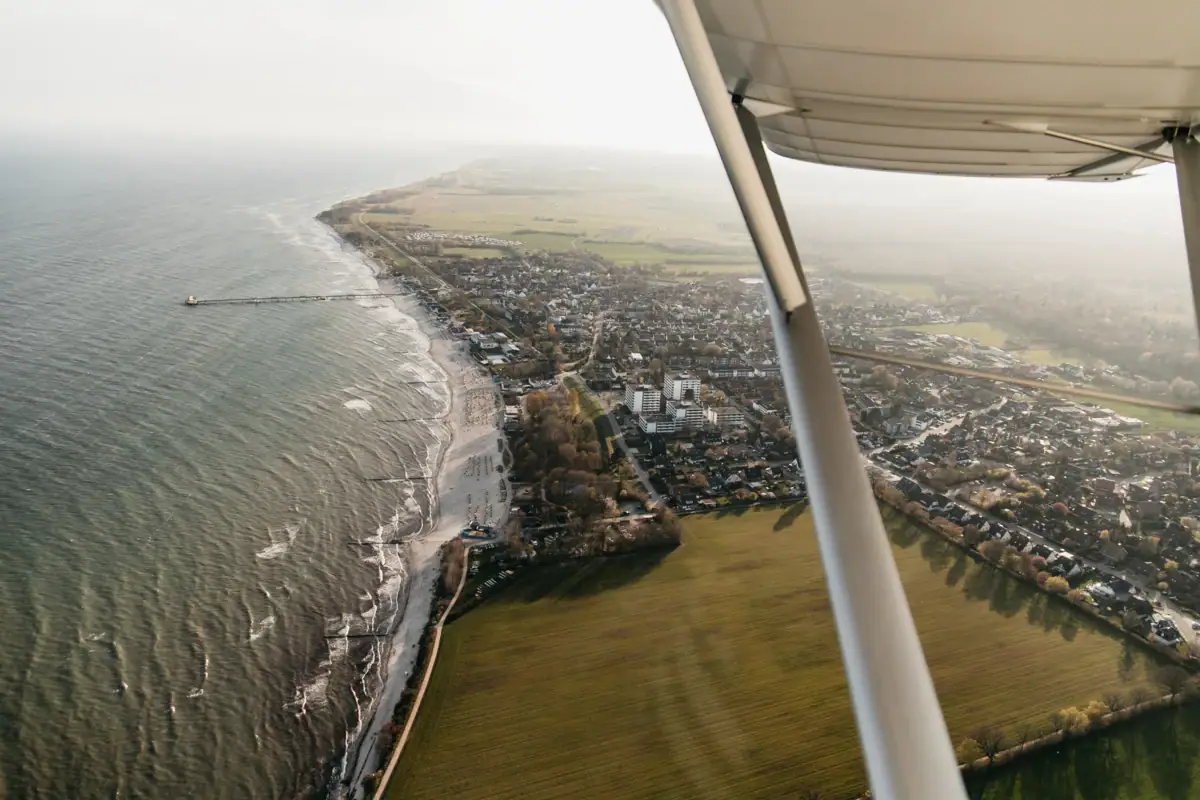 Luchtfoto van een strand en landschap met water op de voorgrond.
