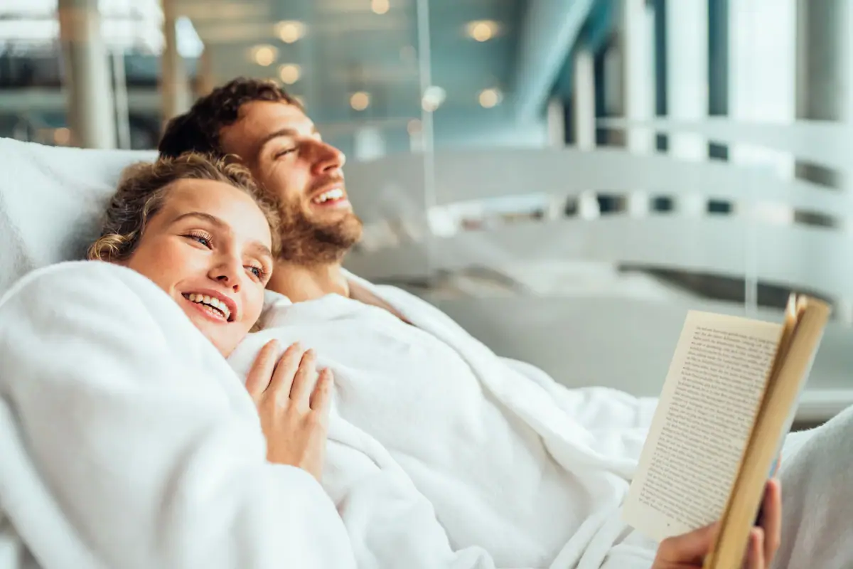 Een man en een vrouw liggen glimlachend in een bed.