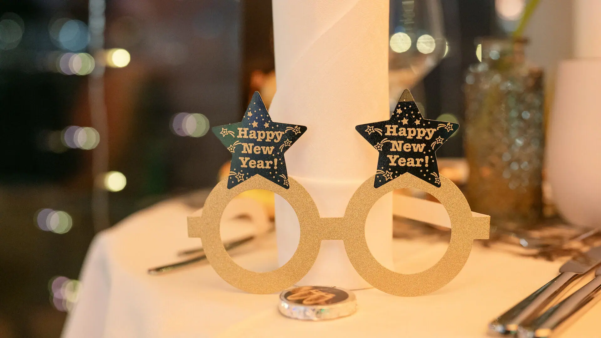 Een papieren bril voor oudejaarsavond met ‘Happy New Year’ op een tafel.