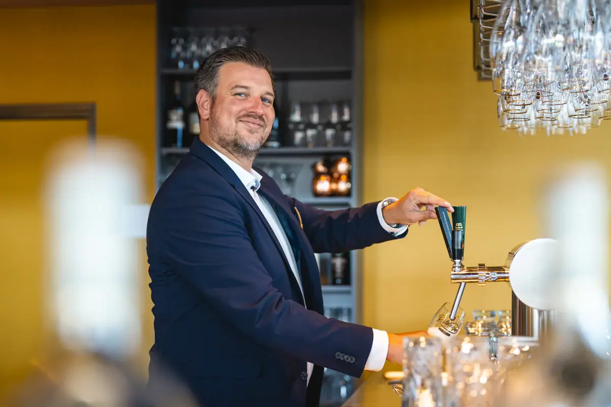 Barman Een man in pak tapt bier uit een tapkraan.