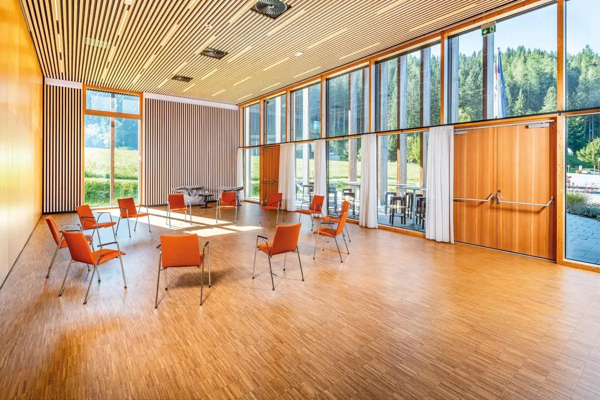 Het conferentiecentrum Werfenweng met tafels en stoelen en grote ramen.