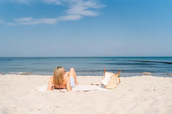 Een vrouw ligt op een handdoek op het strand.