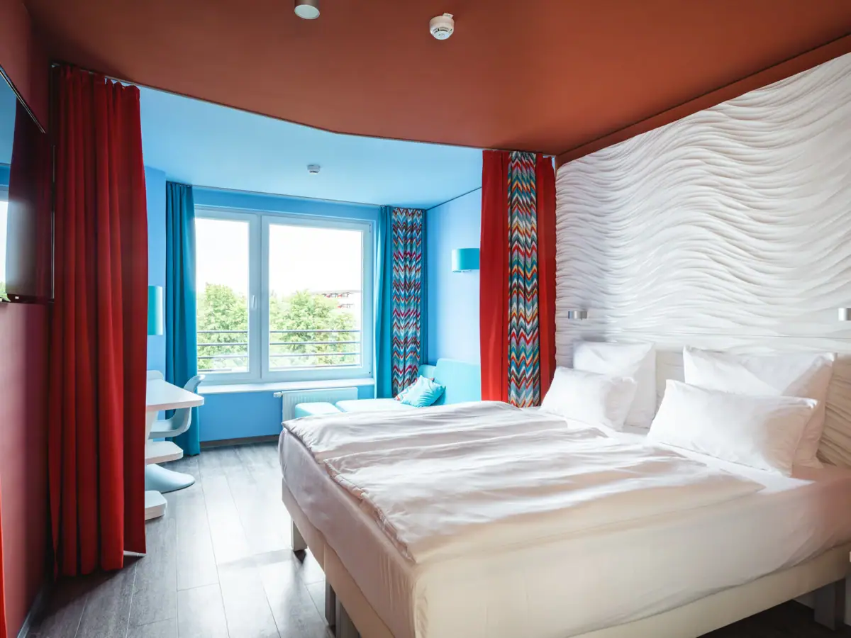 Een kamer met twee bedden en rode gordijnen.