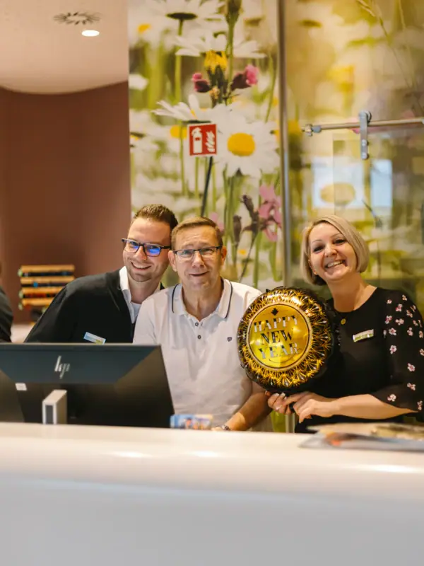 Een groep mensen staat bij de receptie en lacht in de camera.