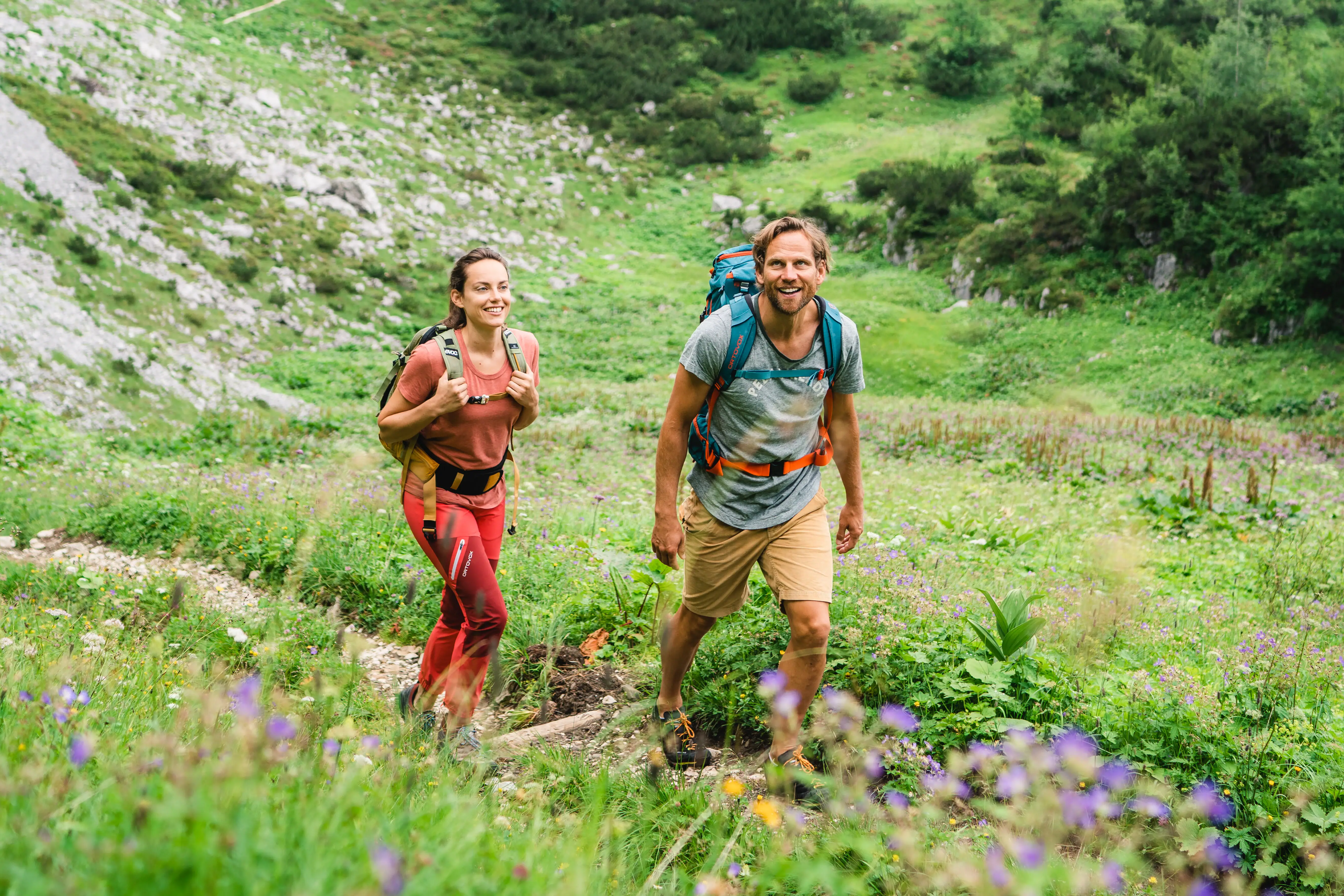 Wandelen Garmisch-Partenkirchen Een vrouw en een man wandelen over een klein pad door een berglandschap.