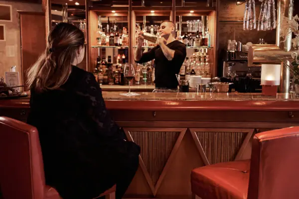 Bistro & Bar Patio Een man en een vrouw in zwarte jurken zitten aan een bar.