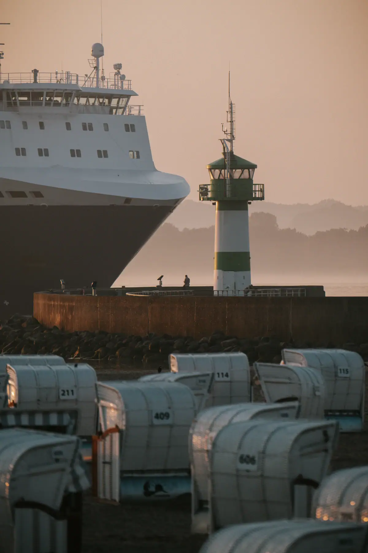 Schip op het water kust de vuurtoren van Travemünde, strandstoelen op de voorgrond