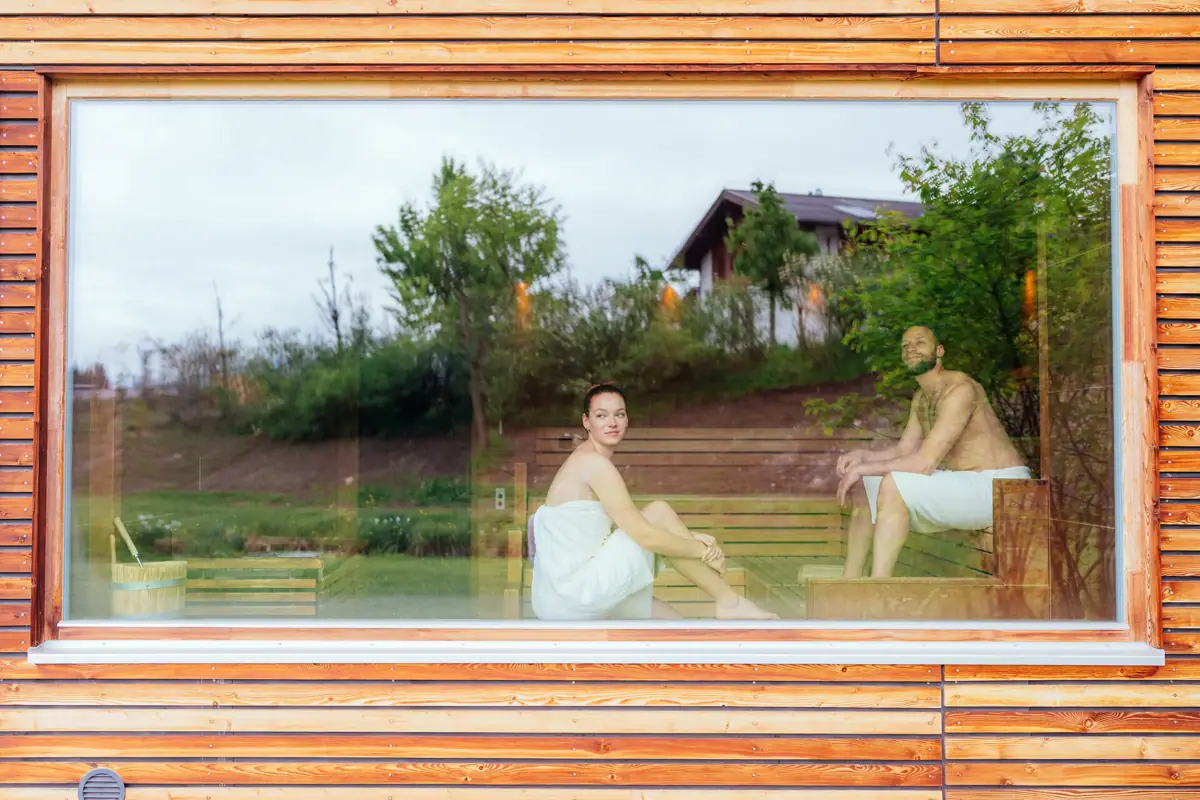 Panoramasauna Een man en een vrouw zitten op een bankje in een sauna.