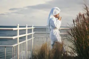 Een vrouw in badjas drinkt uit een beker.