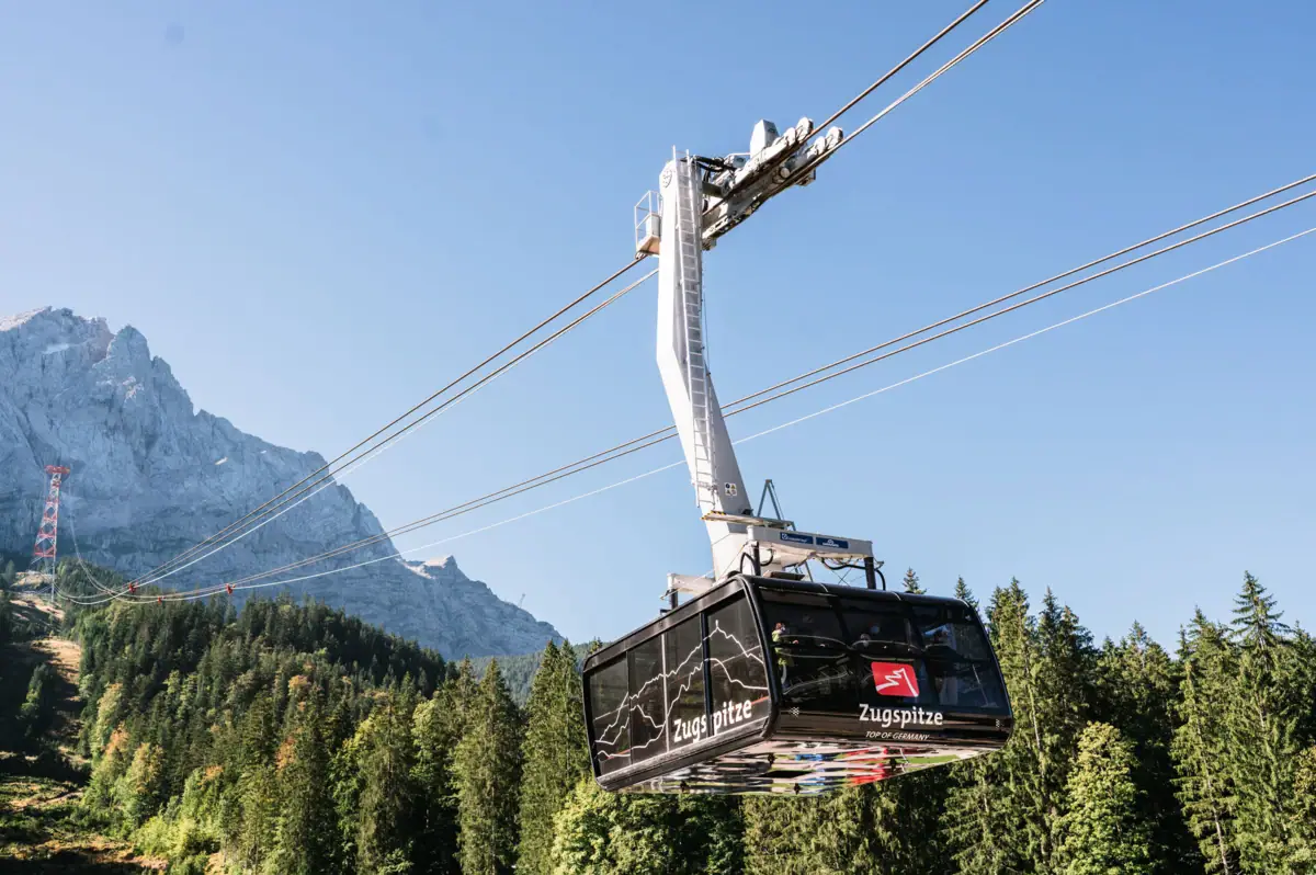 Zugspitze kabelbaan De Zugspitz kabelbaan met bomen en bergen op de achtergrond.
