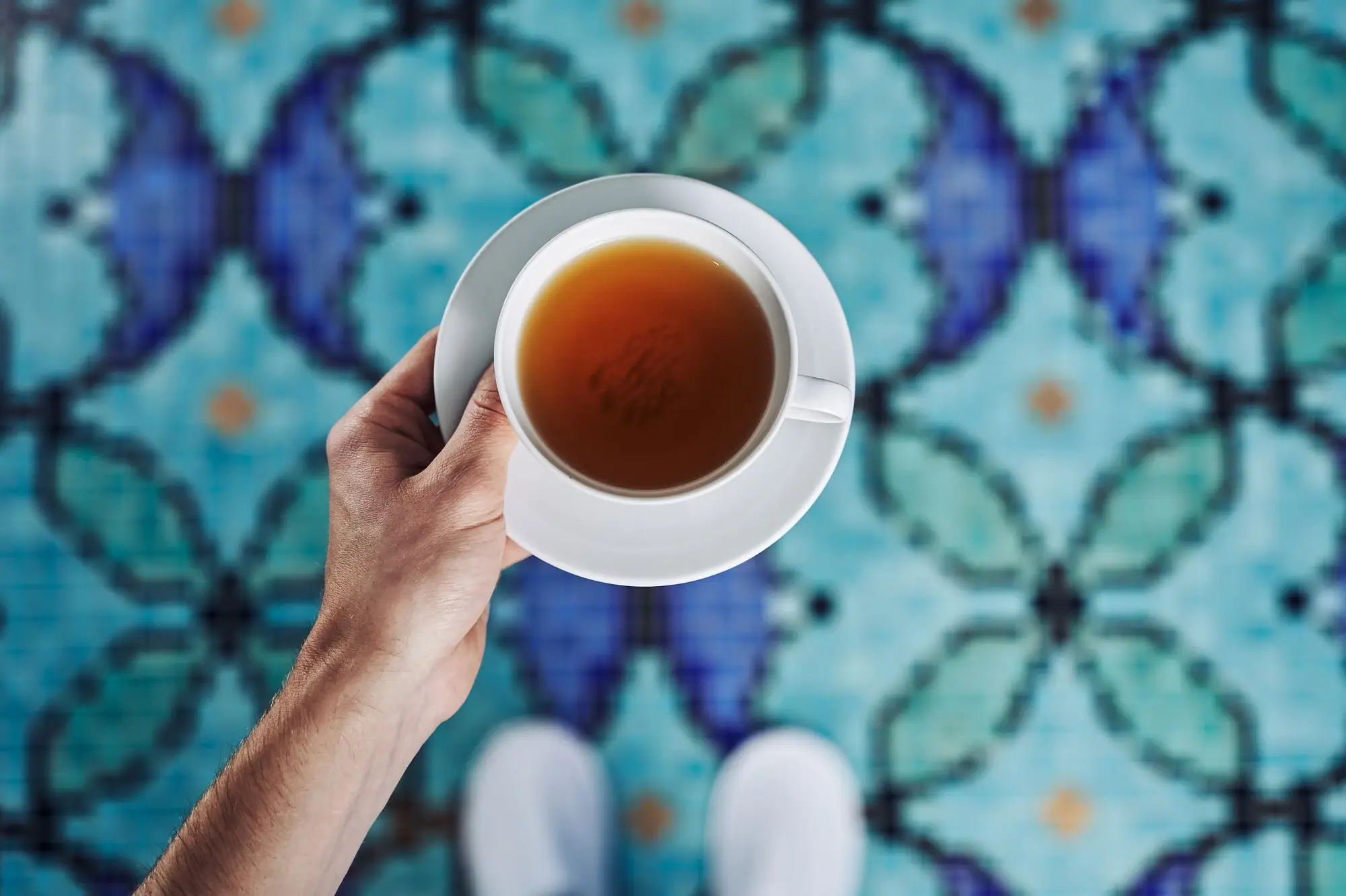 Eén hand houdt een theekopje vast.