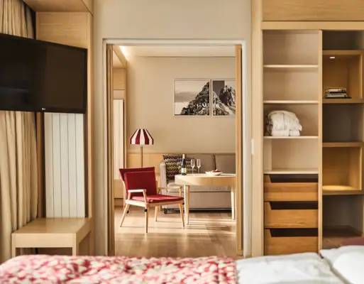 Een hotelkamer met een tv en een zithoek met een bank en een stoel.