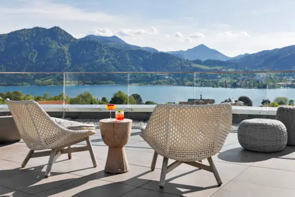 Een tafel en stoelen op een terras met uitzicht op een meer.