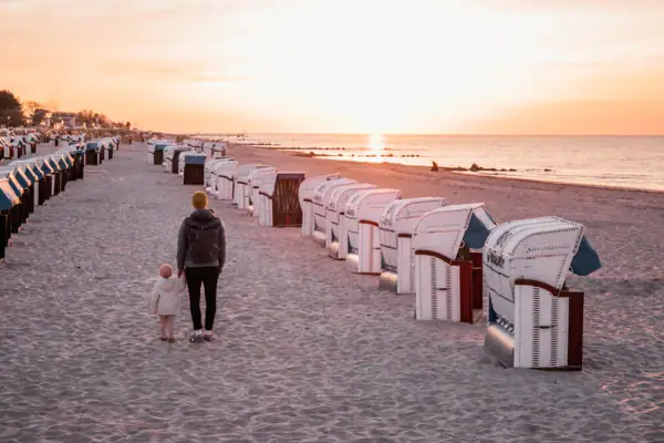 Een vrouw en een kind lopen over het strand.