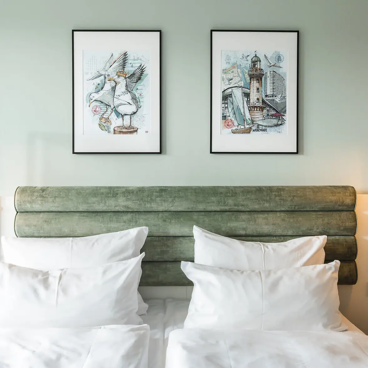 Kamers en suites in het aja Warnemünde Bed met witte kussens en groen hoofdeinde, geflankeerd door twee lampen.