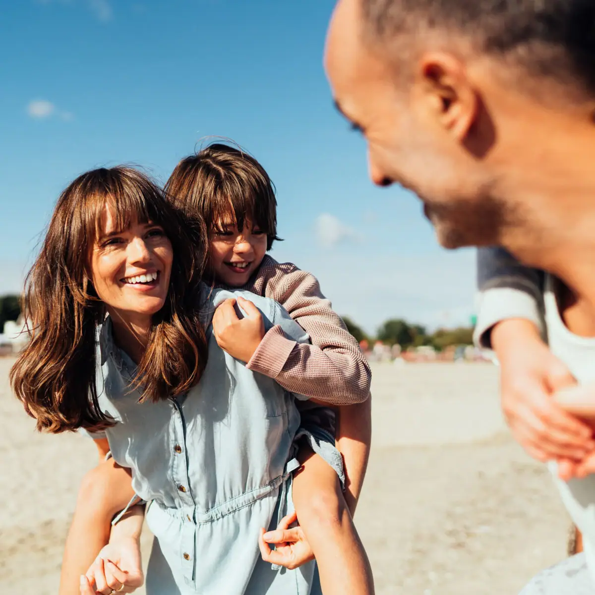 Een man en een vrouw houden een kind vast op het strand.