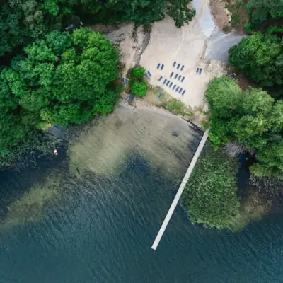 Een loopbrug over een waterlichaam met stoelen en bomen.