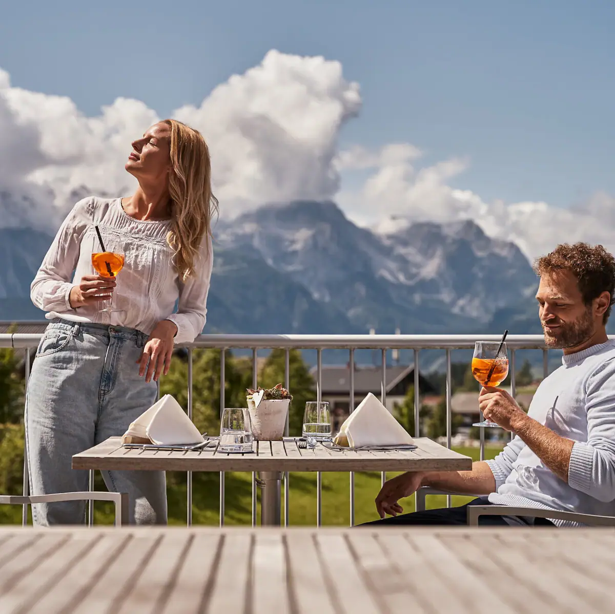Een man en een vrouw drinken uit een glas op een balkon.