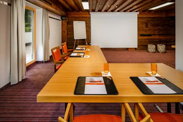 Vergaderzaal Een kamer met een groot wit scherm en verschillende tafels.