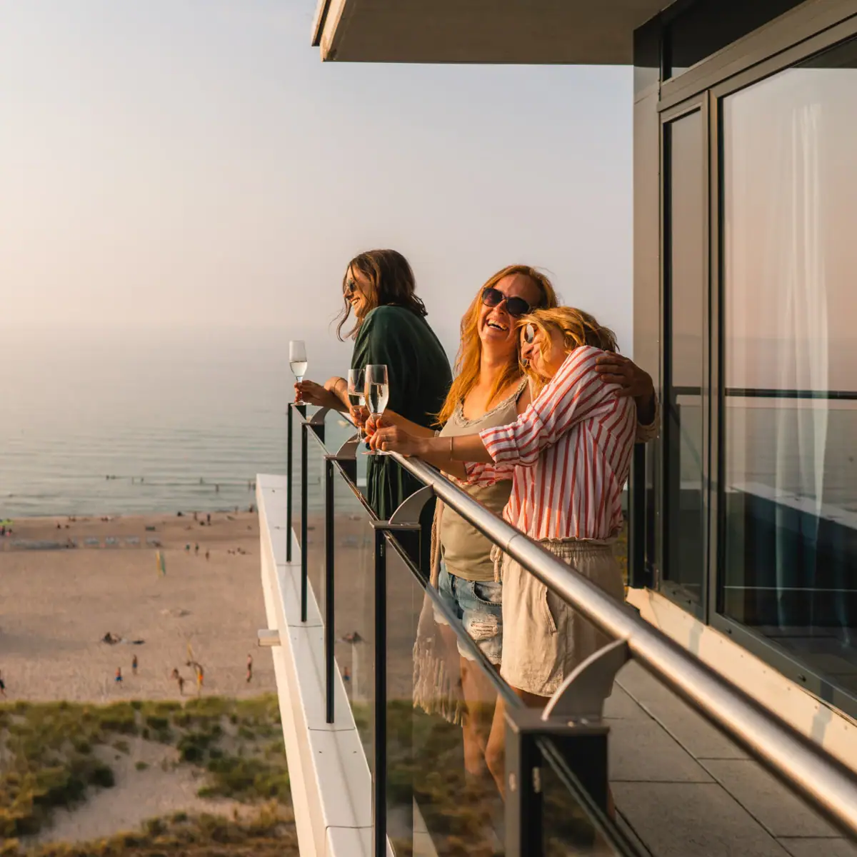 Balkon bij aja Warnemünde Een groep vrouwen staat op een balkon dat uitkijkt over het strand.