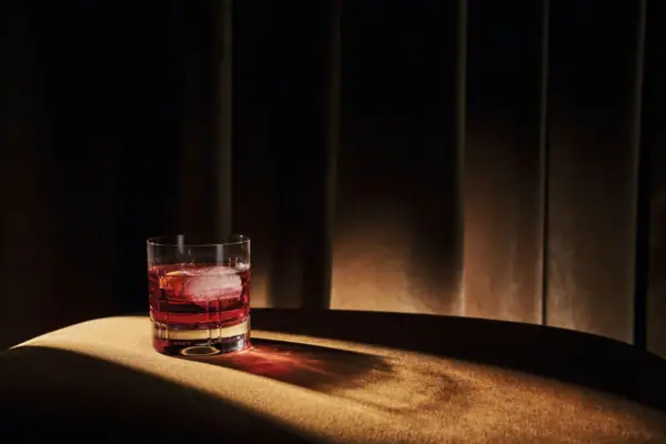 Een glas rode vloeistof en ijs op een tafel.