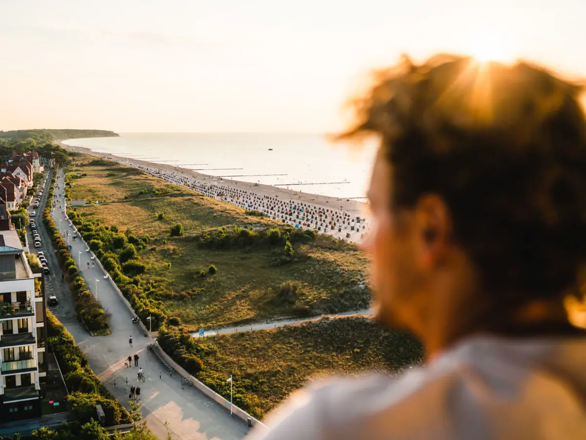 Vooruitzichten bij aja Warnemünde Een man kijkt uit over het strand van Warnemünde.